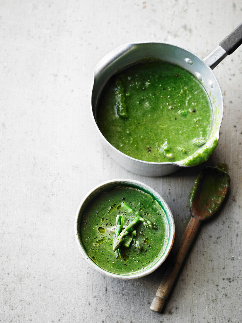 Green asparagus soup in pot and bowl