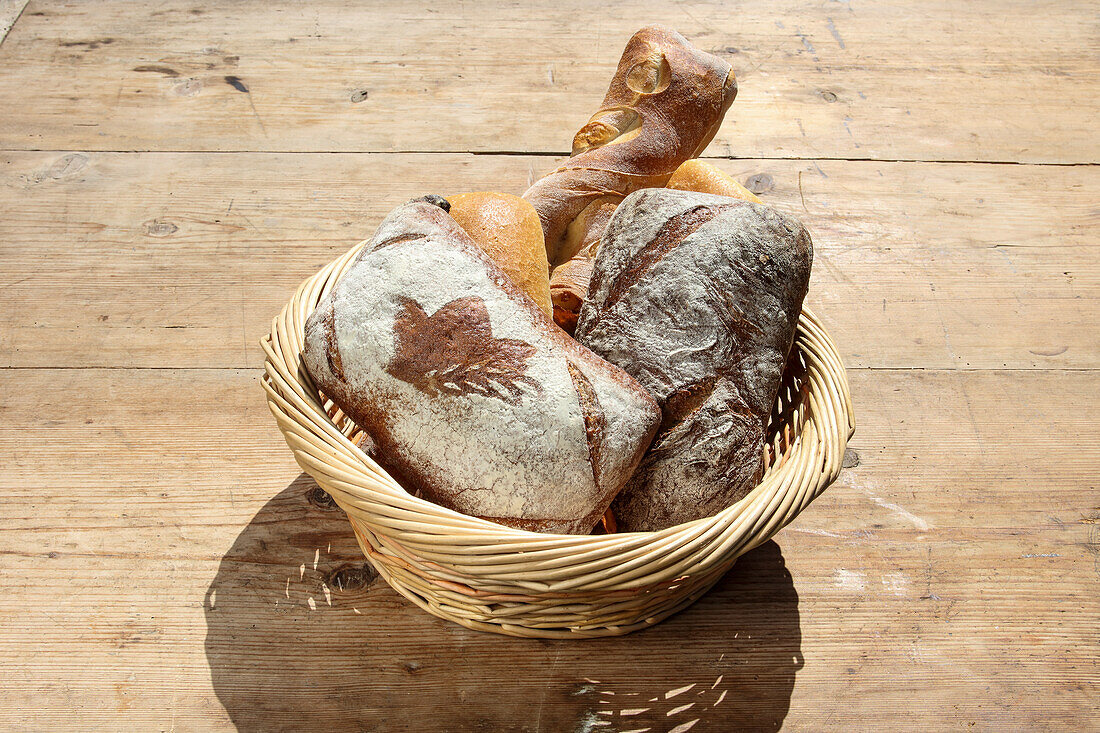 Various freshly baked goods in a basket on a wooden table