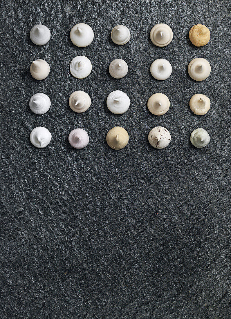 Assorted meringue dots in rows on a grey background