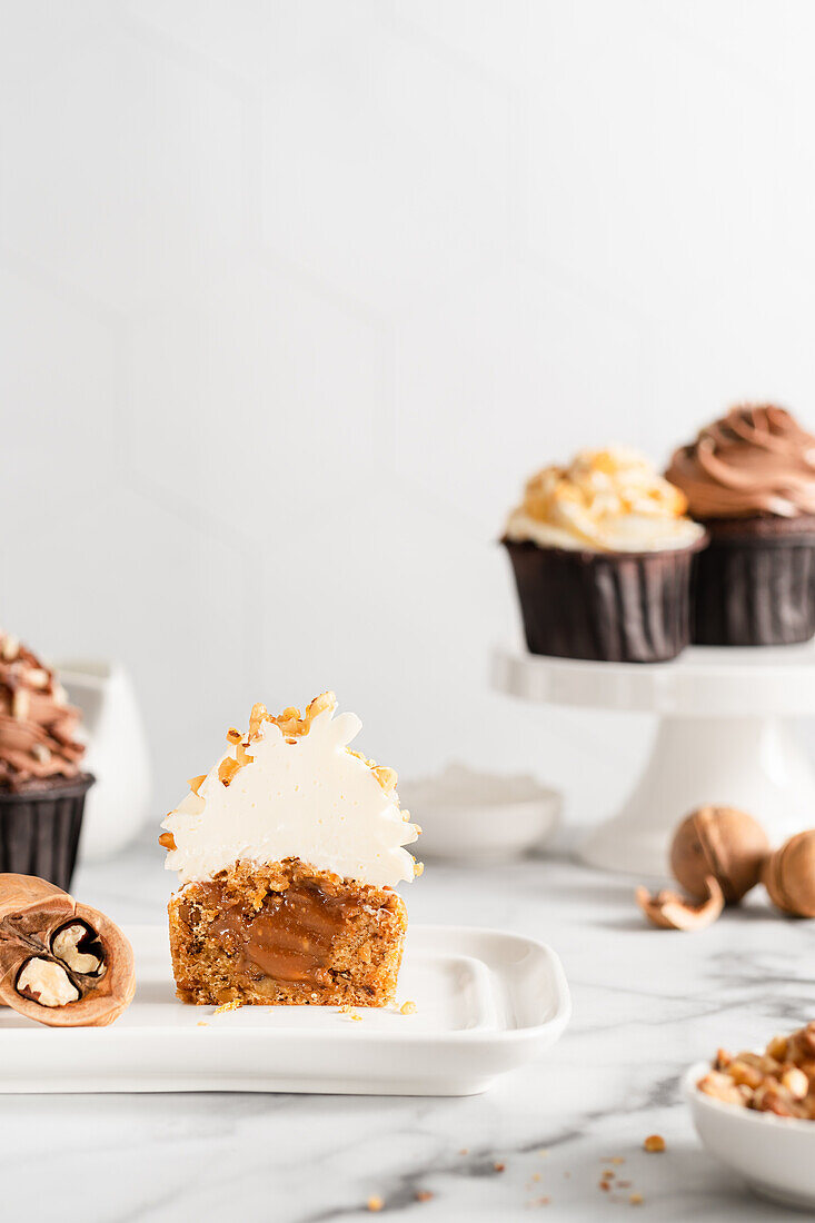 Carrot cupcakes with vanilla frosting and chopped walnuts