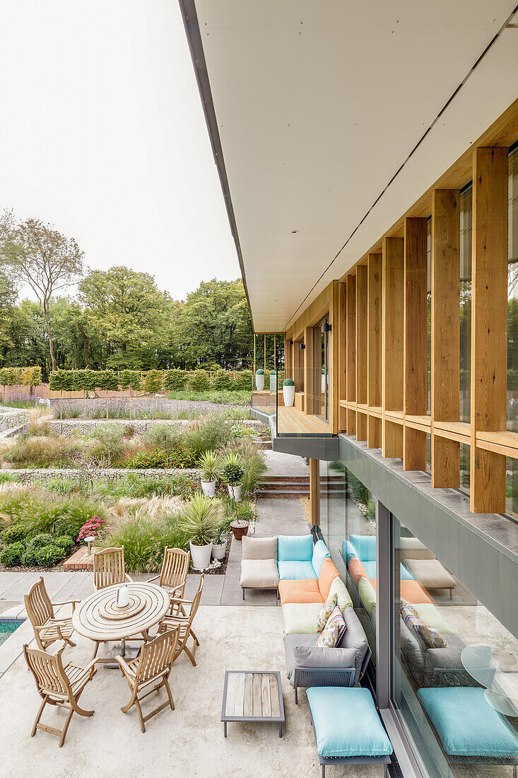 Terrasse mit Sofa und Esstisch am Architektenhaus mit großem Garten