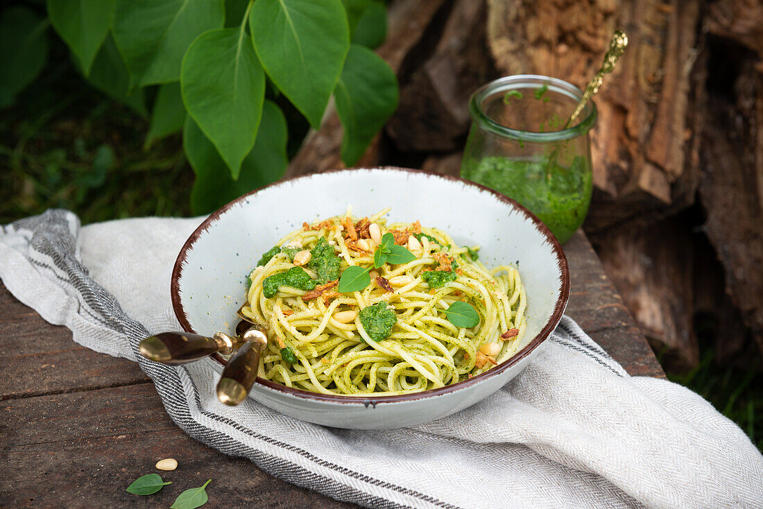 Spaghetti with vegan spinach pesto, pine nuts and roasted onions