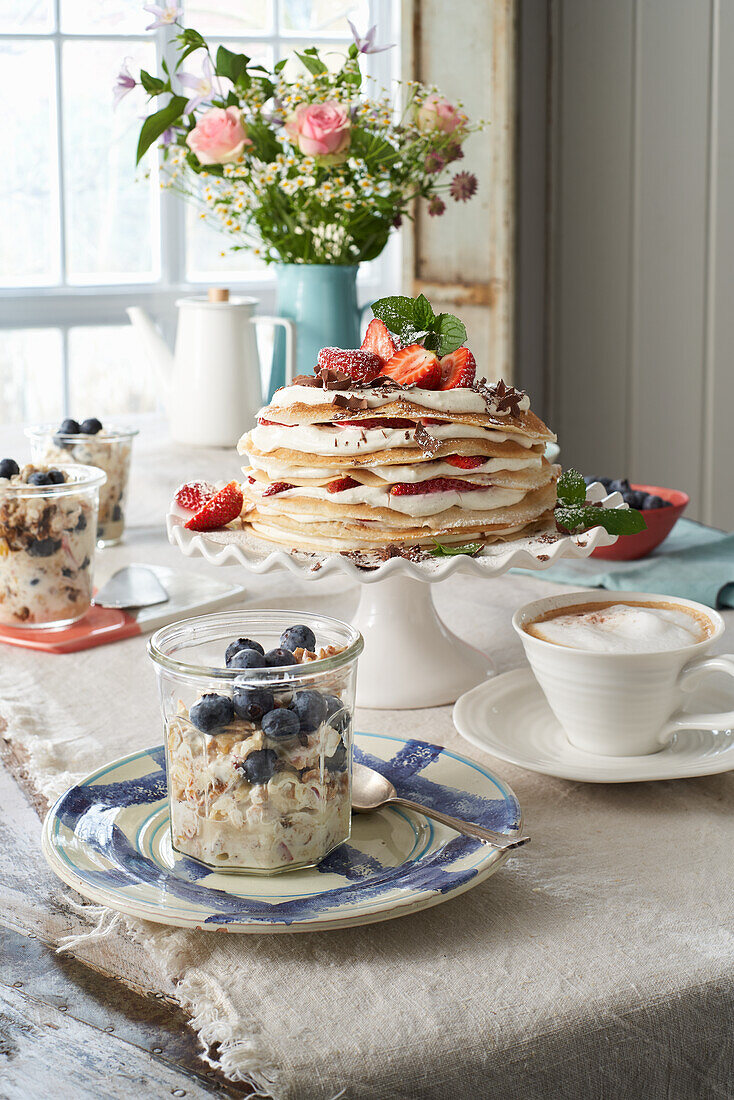 Pfannkuchen-Torte und Blaubeer-Bircher-Müsli auf Frühstückstisch
