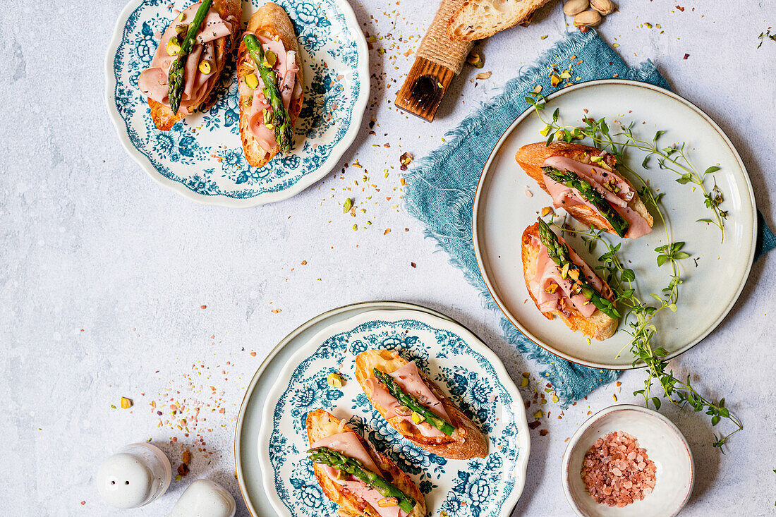 Toasted baguette slices with mortadella and green asparagus