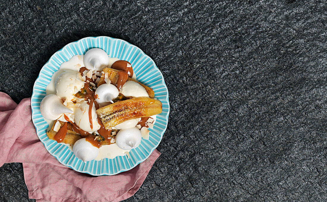 Caramelized bananas with meringue, caramel sauce, ice cream, coconut flakes, and whipped cream