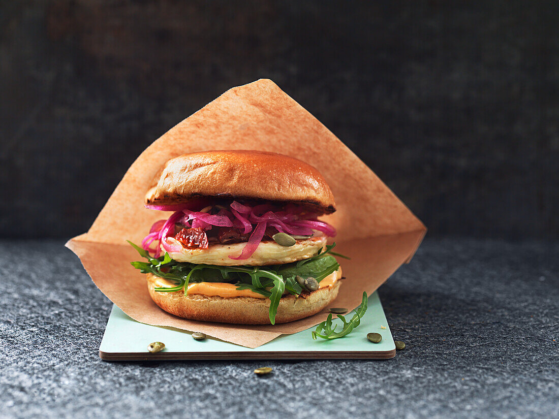 Vegetarian burger with halloumi, rocket, pickled onions, and Sriracha