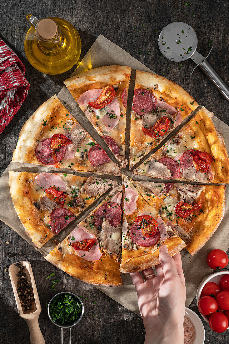 Pizza with salami, ham, and tomatoes