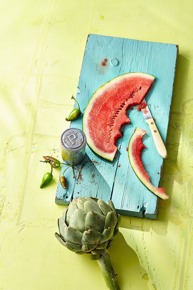 Artischocke und eine angebissene Scheibe Wassermelone