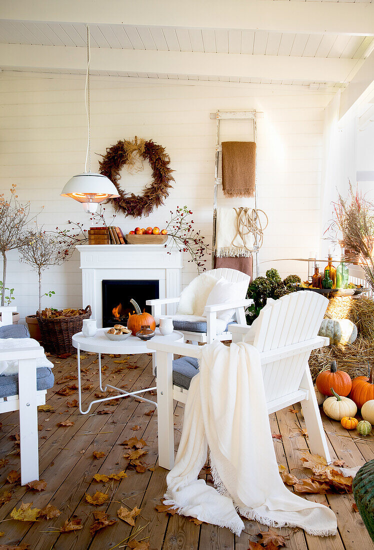 Gemütliche, herbstliche Veranda mit weißen Stühlen