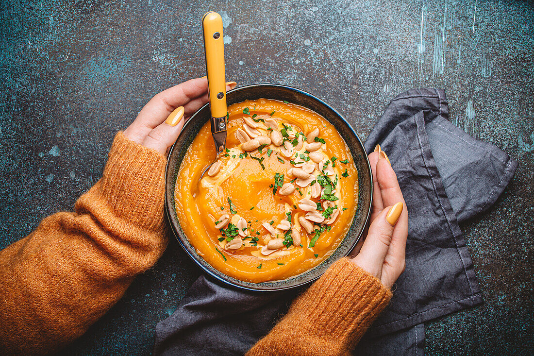 Female hands holding bowl of cream of pumpkin soup