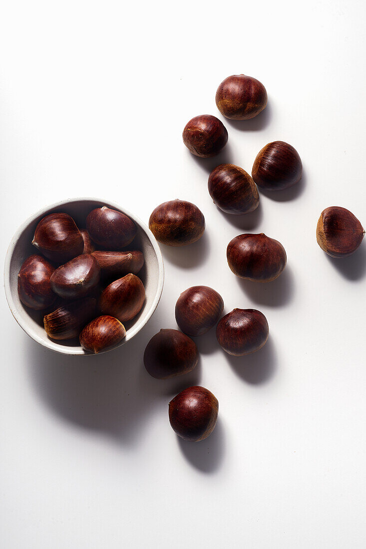 Top view of raw uncooked chestnuts on white background
