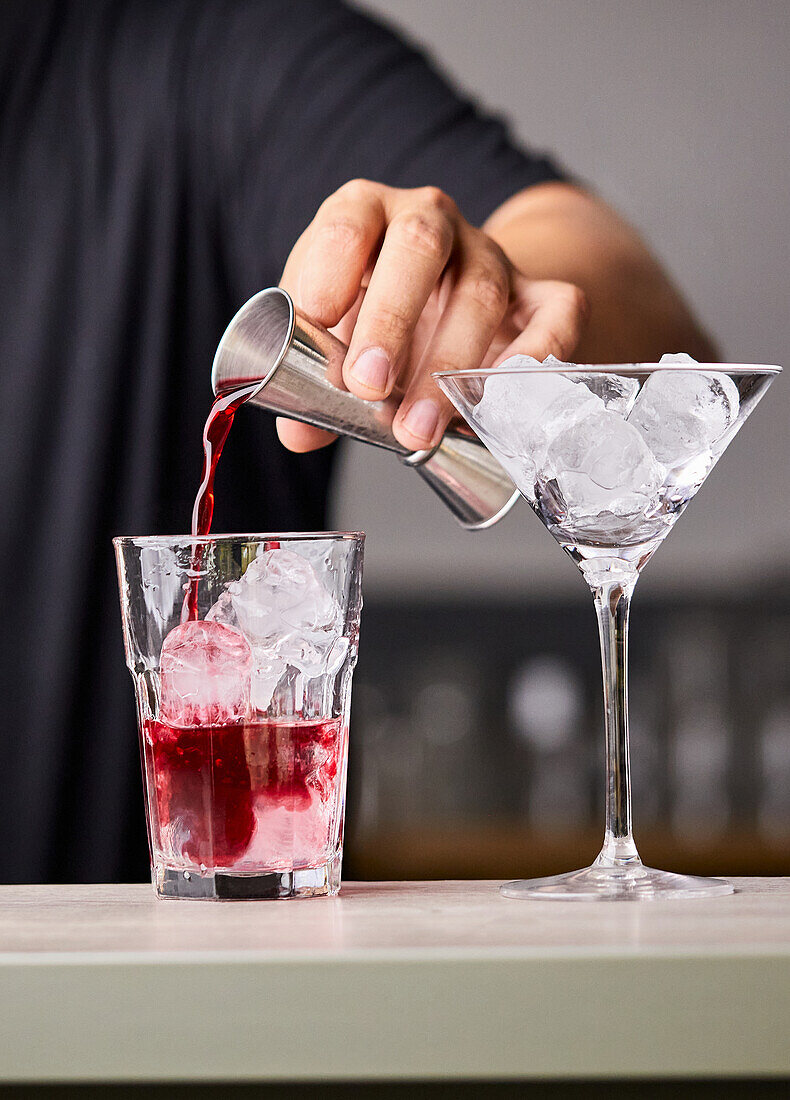 Cosmopolitan-Cocktail zubereiten: Cranberrysaft in ein Glas gießen