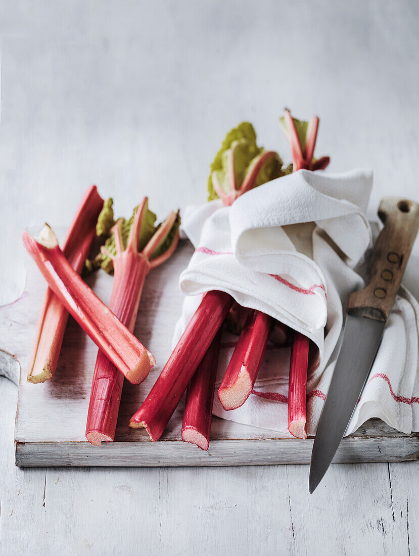 Rhubarb washed on a cutting board with a cloth and knife