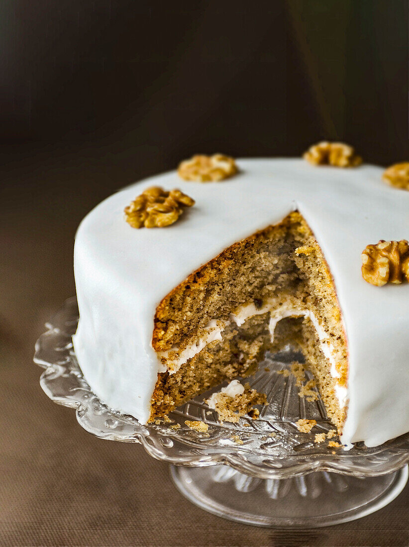 Festive walnut cake on cake stand with a serving cut out