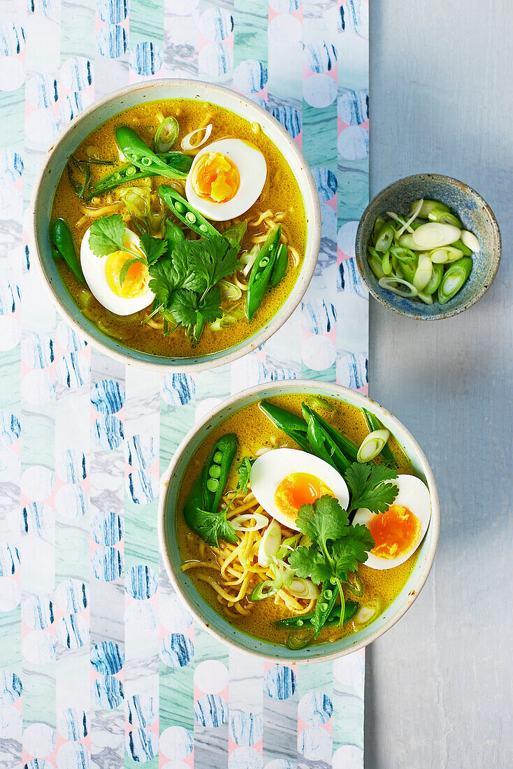 Golden noodle soup with peas and boiled egg