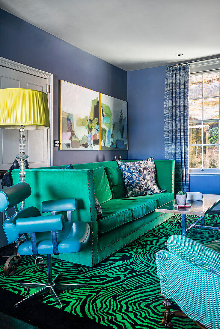 Grünes Sofa, Vintage Lederstuhl und Teppich mit Malachitmuster im Wohnzimmer mit blauen Wänden