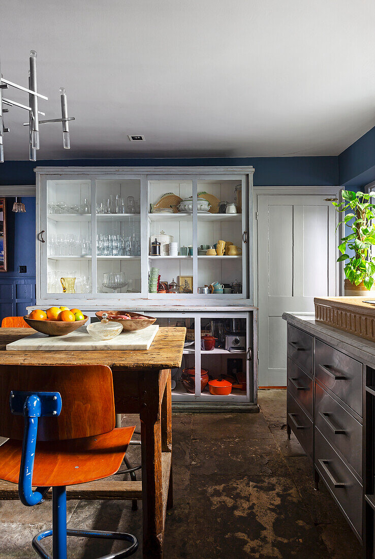 Industrial table with vintage bar stools, in the background glass cabinet in the kitchen