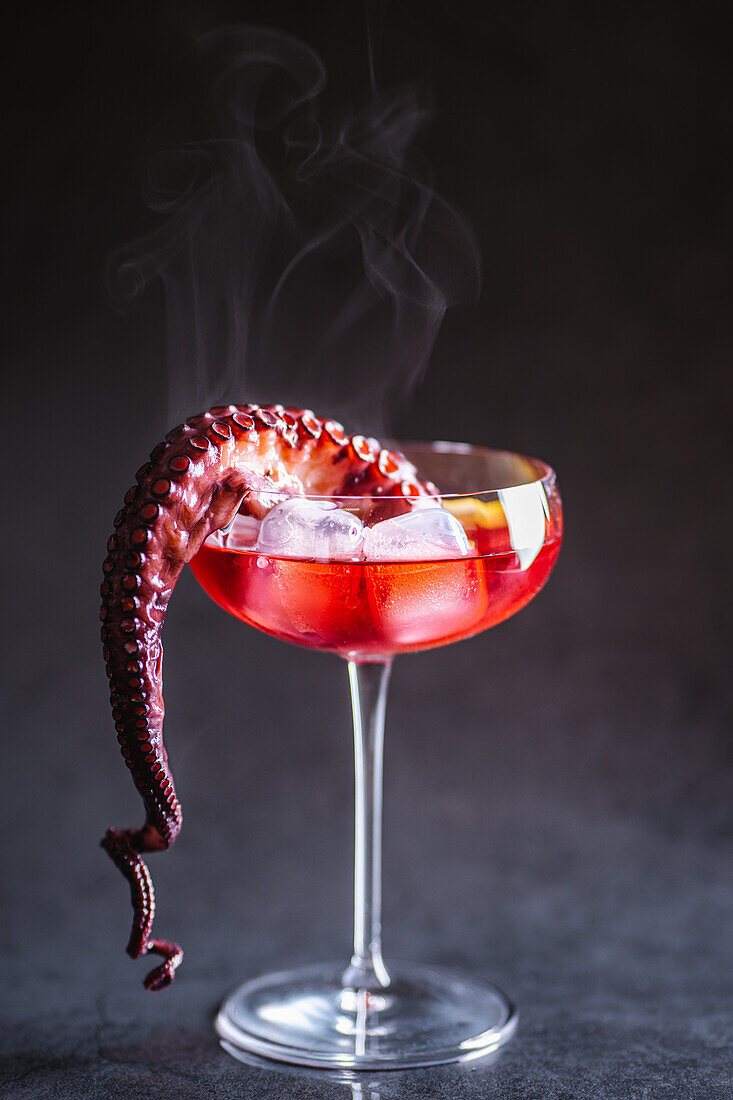 Cocktail serviert mit Eiswürfeln und Oktopus-Tentakel