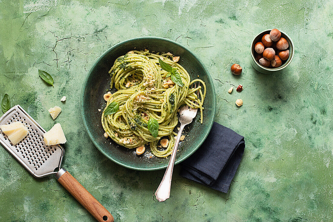 From above ceramic plate with hazelnut pesto spaghetti on green table surface