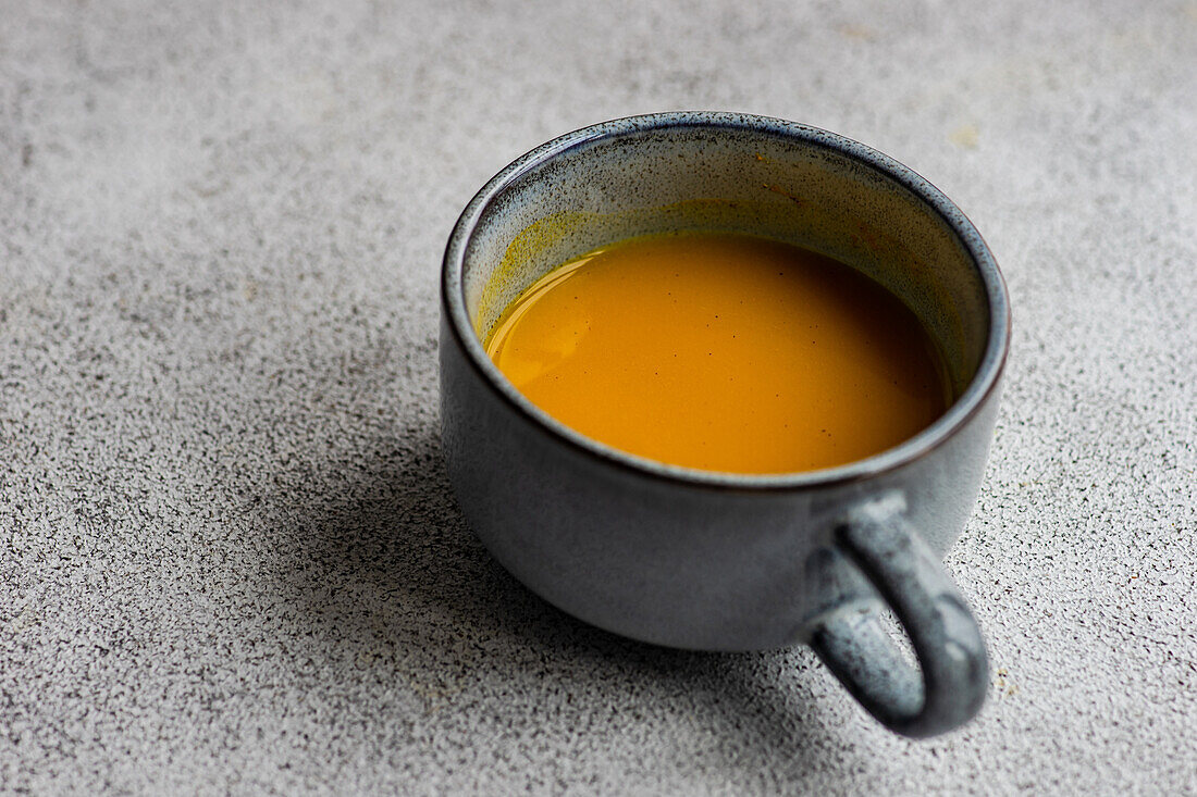 From above spiced turmeric moon milk drink in grey ceramic cup on stone table