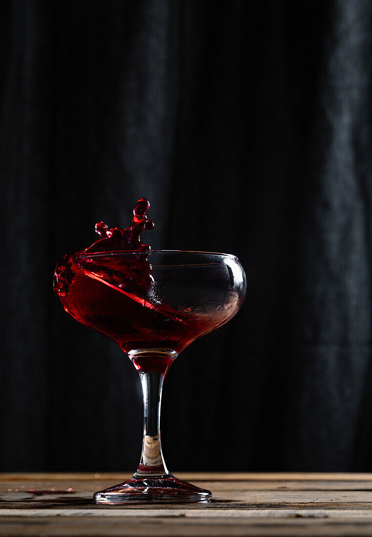 Rotwein mit Schwung im Weinglas vor schwarzem Hintergrund