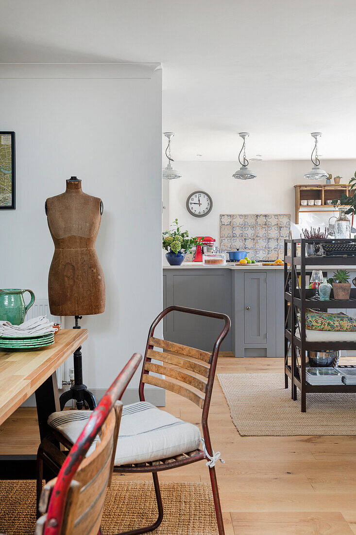 Dining area with wooden and metal chairs, dress form in the background