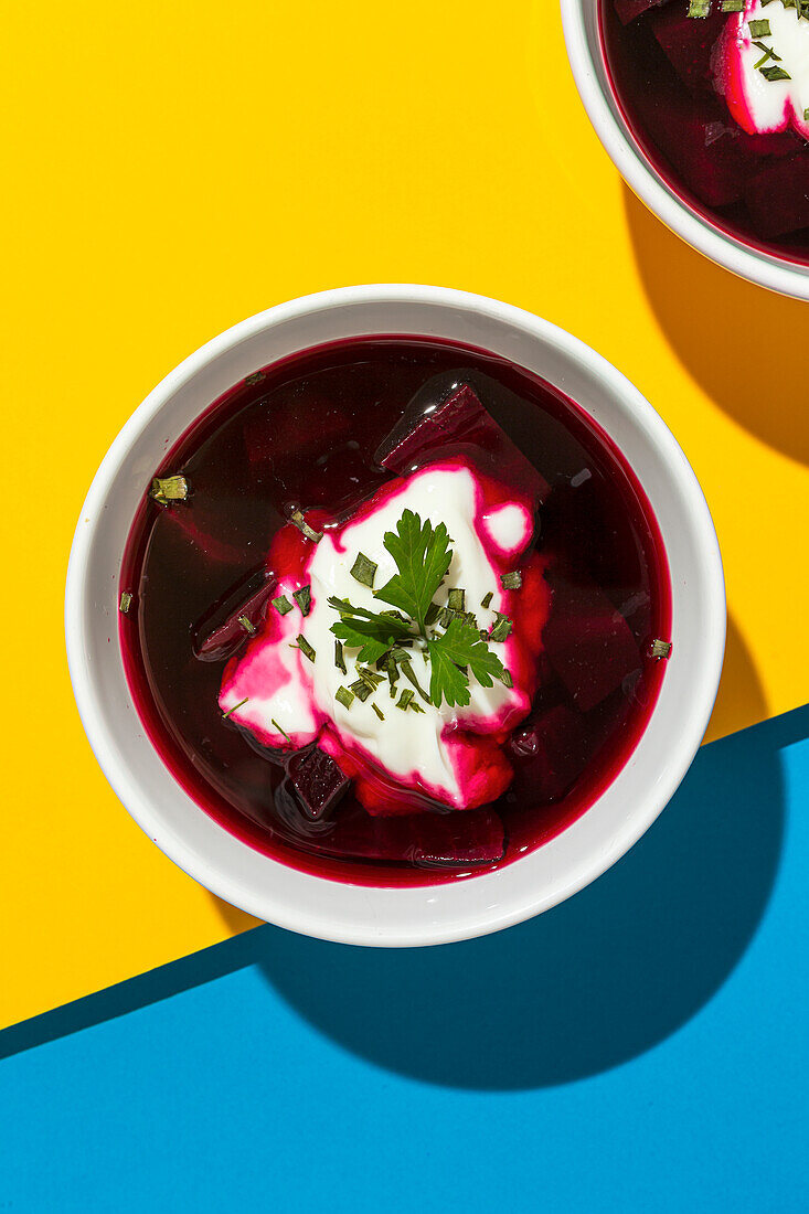 Bowls with tasty borscht made with beetroot on background of colors of Ukrainian flag