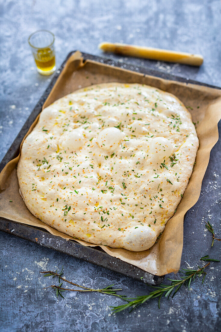 Veganes Foccacia mit Rosmarin und Sesam ungebacken auf Backblech