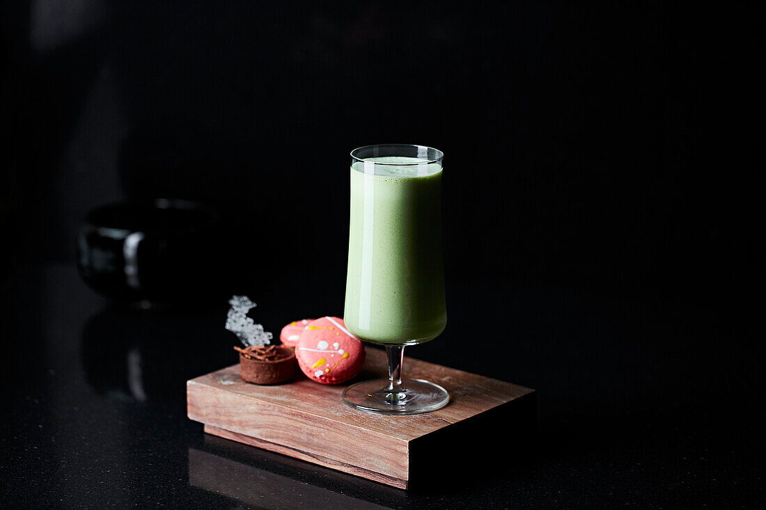 Matcha drink served with macarons on a wooden platter