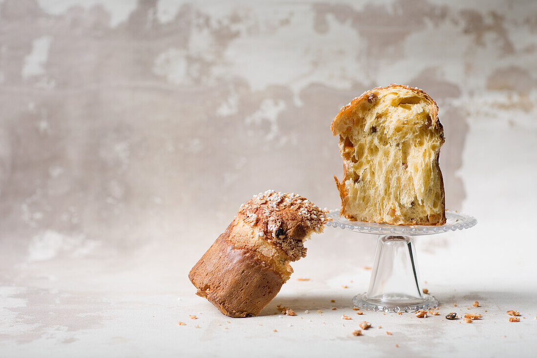 Halved panettone on and next to a glass cake stand