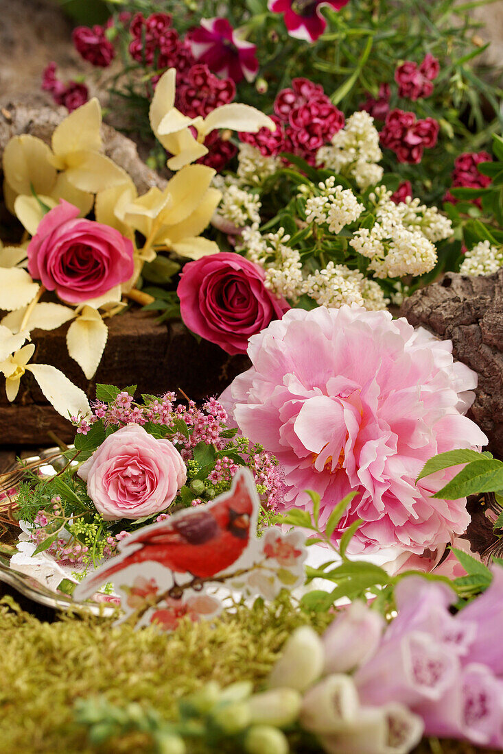 Still-life arrangement of peony, roses, privet, foxglove and spiraea and cardboard bird cutout