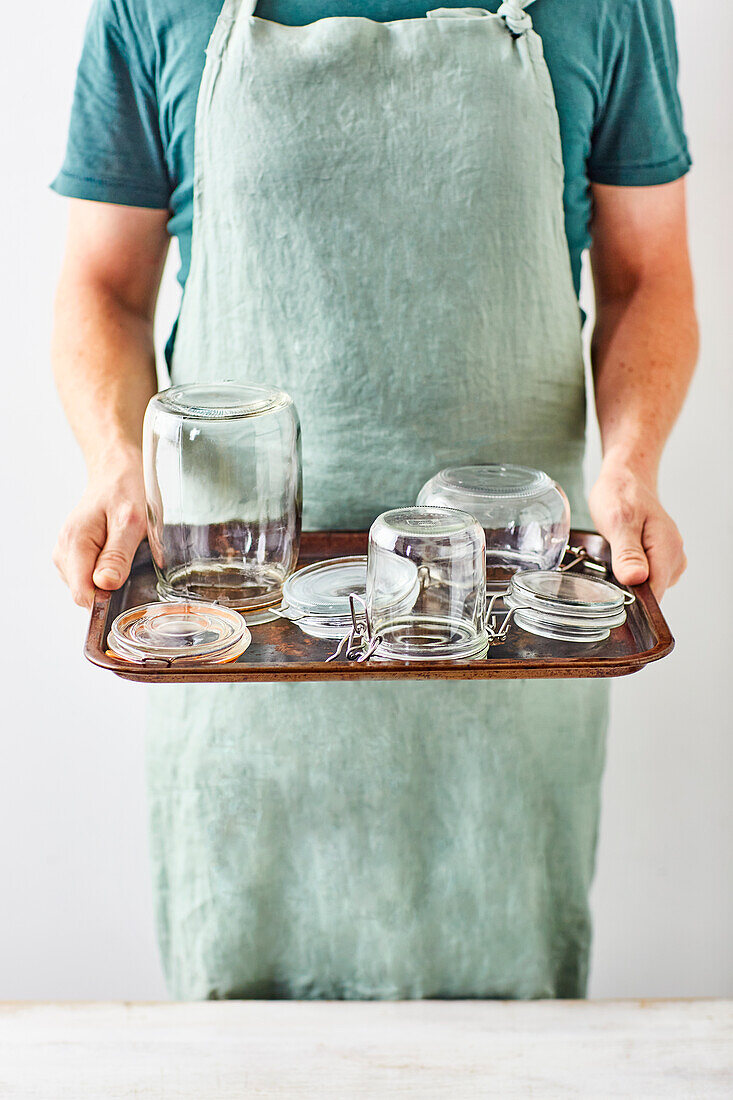 Man holding tray with prepared preserving jars