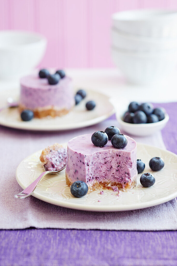 Blueberry Cheesecake with fresh blueberries on purple background two portions