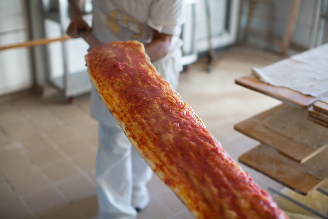 Long pizza on a pizza shovel in a pizzeria