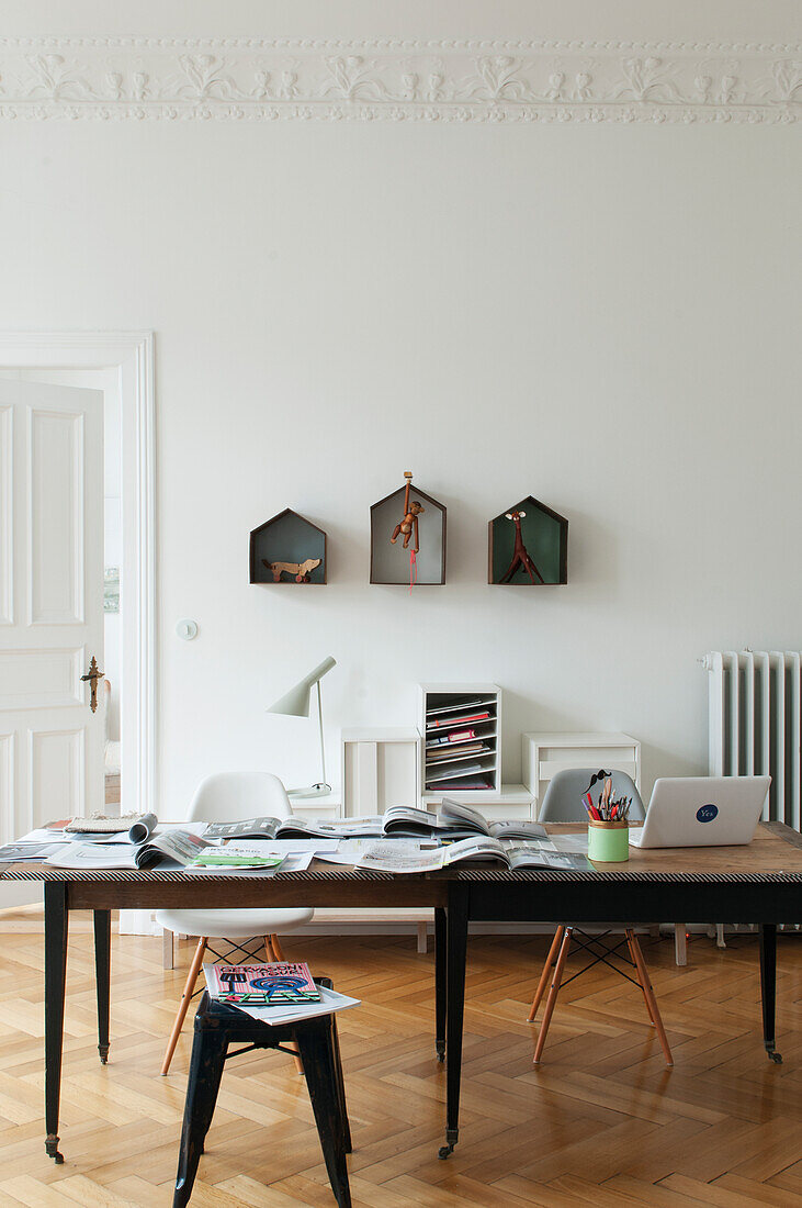 desk on casters with classic chairs, behind it a decorative box on a white wall