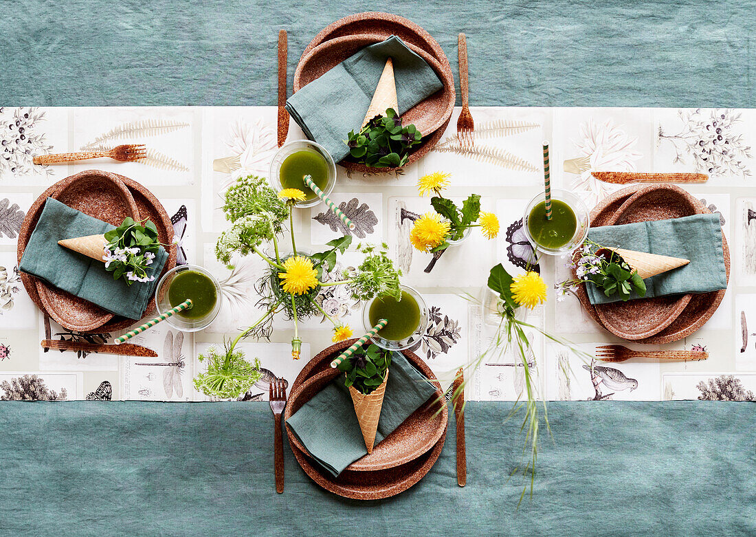 Sommerlich gedeckter Tisch mit braunen Tellern und Löwenzahnblüten