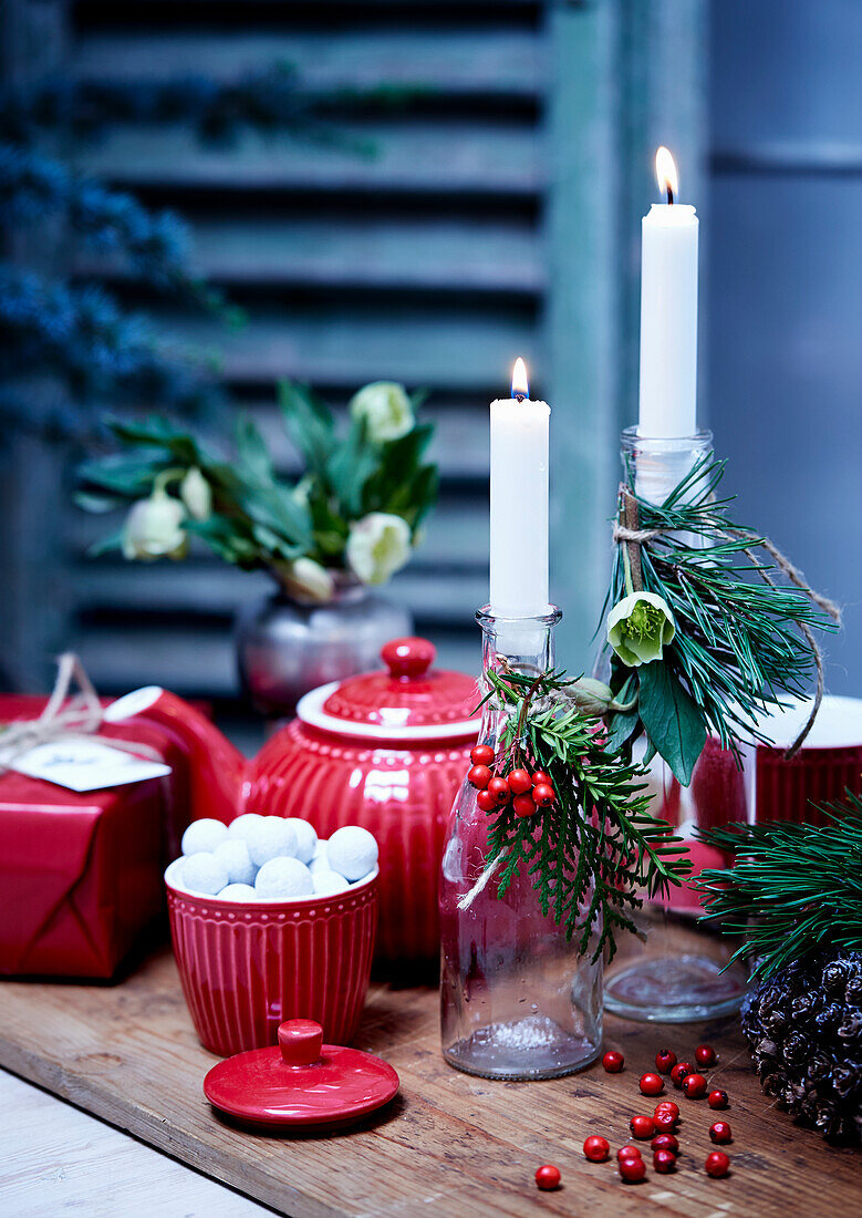Red crockery and festively decorated bottles used as candle holders