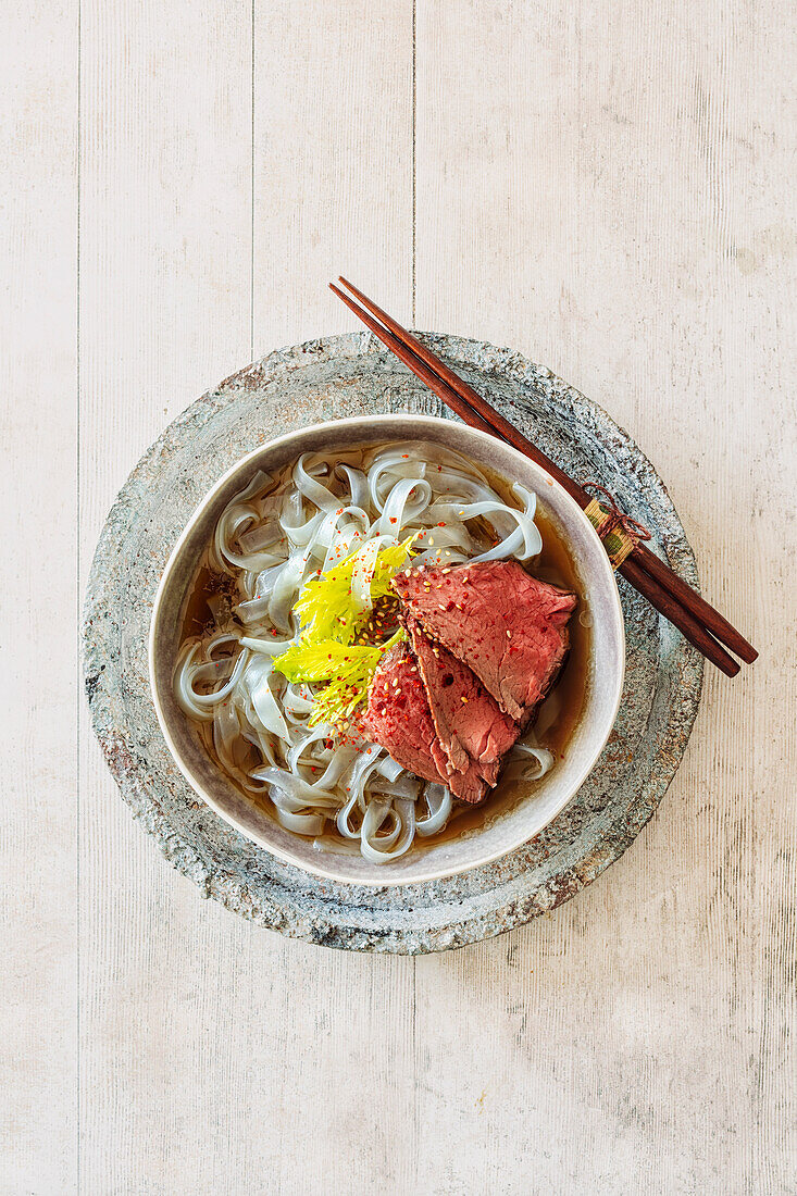 Vietnamese beef soup (Pho Bo) with bean sprouts, ribbon noodles, and slices of bison medallion