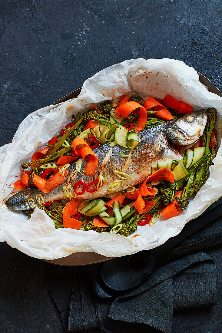 Whole steamed sea bass with vegetables in parchment