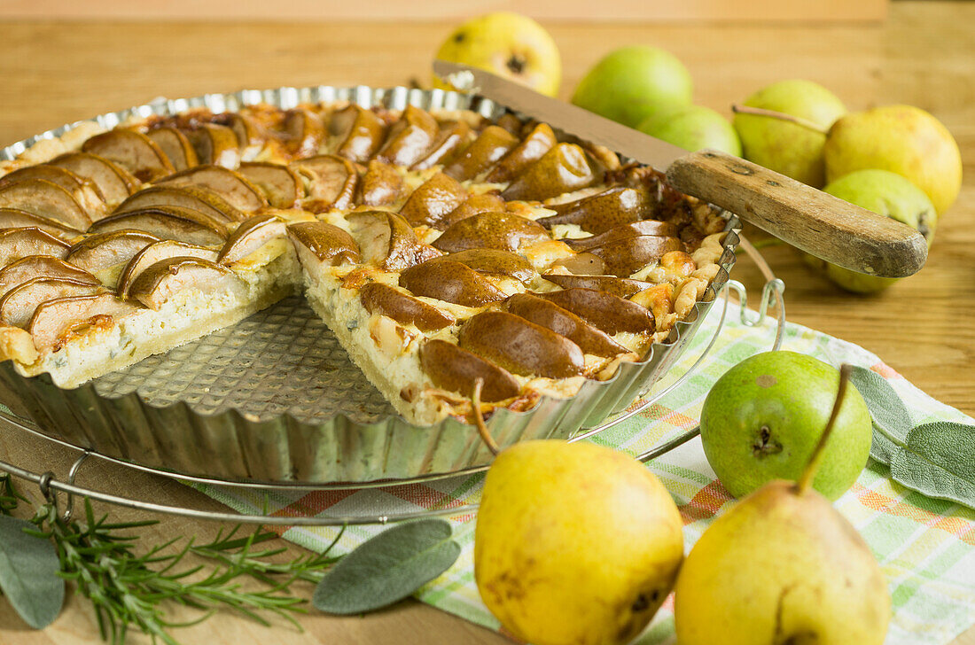 Pear tart in a tart mould on a rustic wooden table