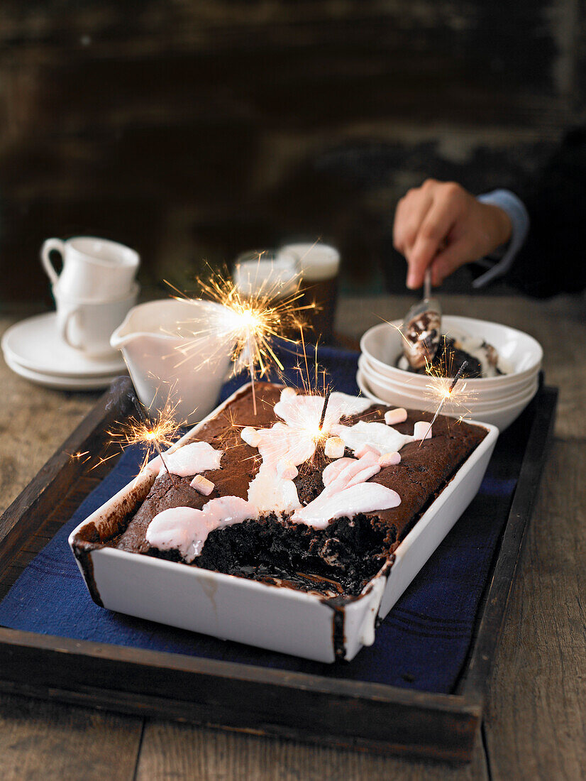 Sticky chocolate pudding with marshmallows and lit sparklers