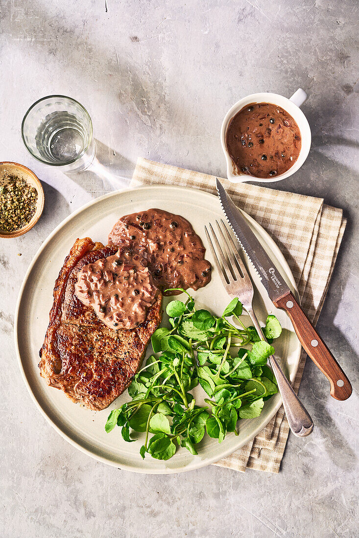 Steak with pepper sauce and watercress salad