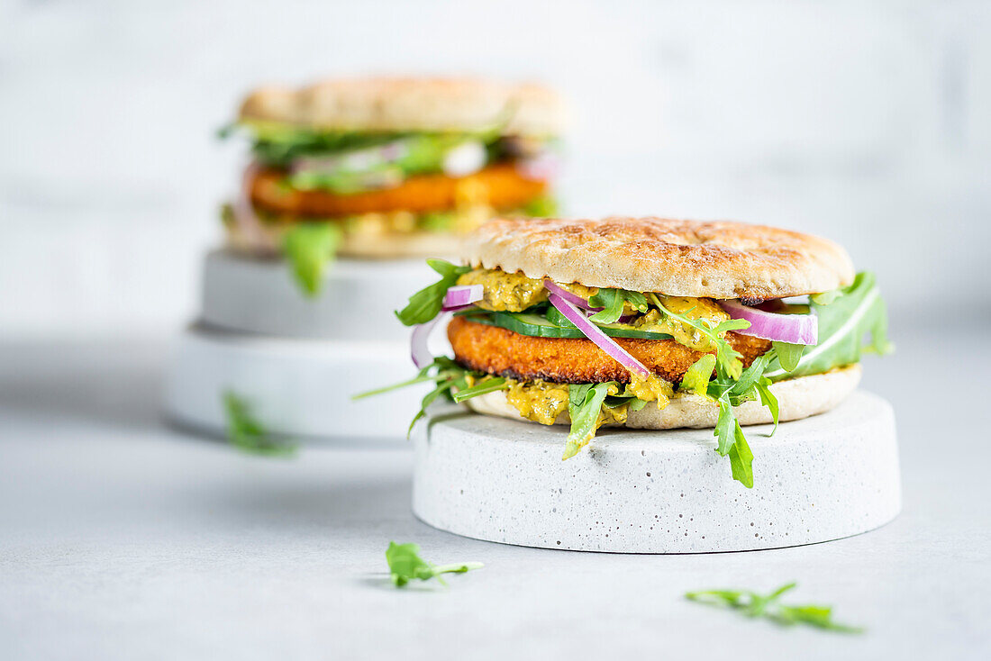 Fish burger with curry sauce, rocket and red onions