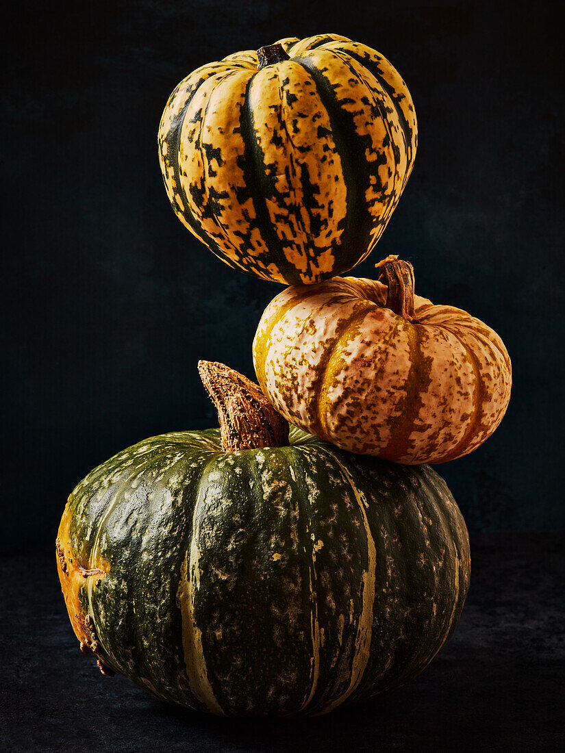 Three pumpkins stacked against a black background