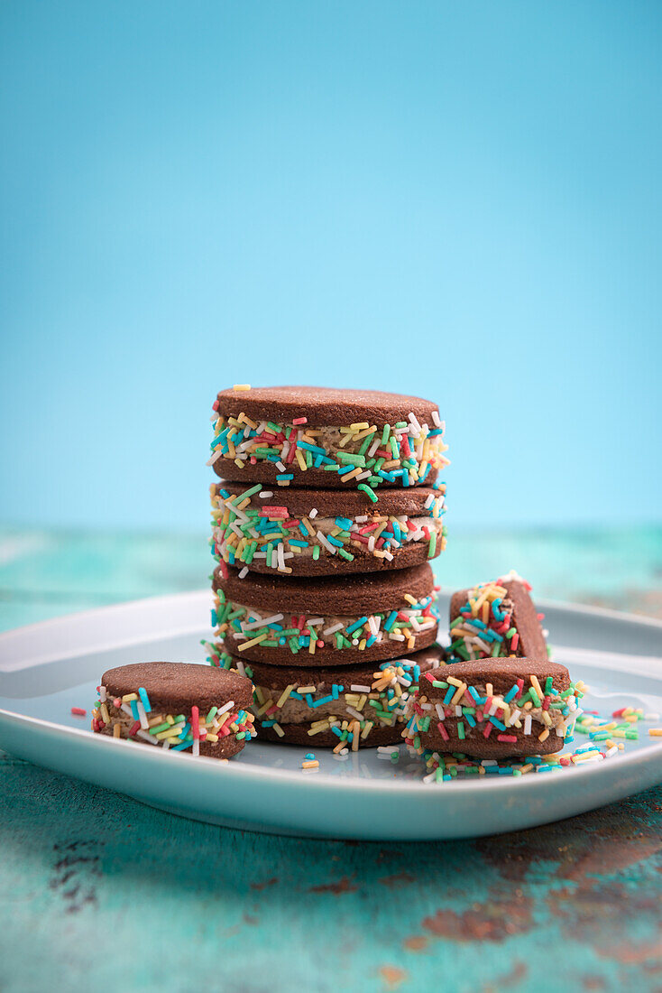 Vegan shortbread biscuits with a chocolate cream filling and colourful sugar sprinkles