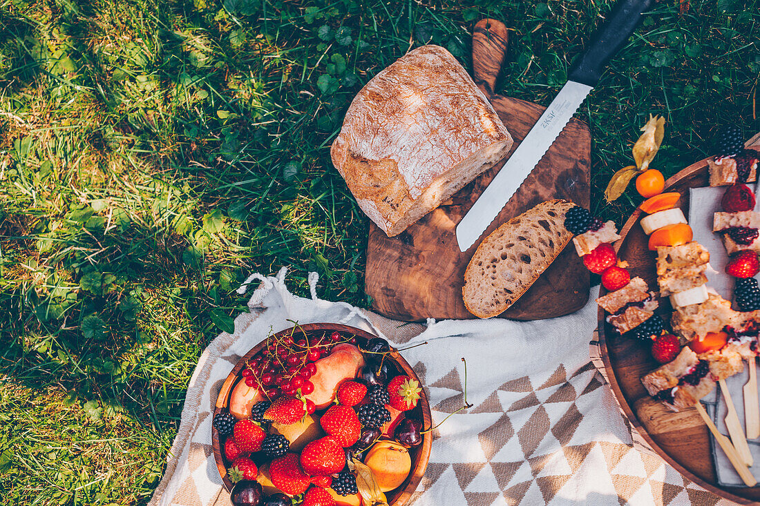 A picnic in the garden with bread, vegetarian sandwich kebabs and fruit