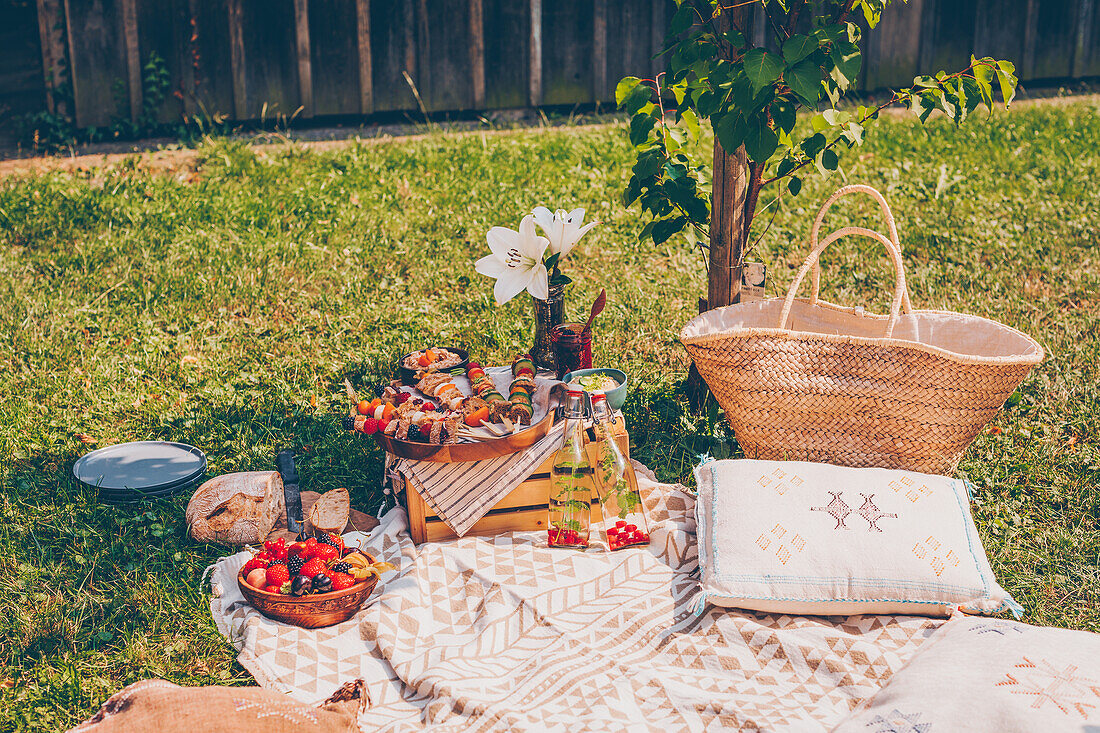 Picknick im Garten mit Sandwich-Spießen, Obst, Brot und Getränk