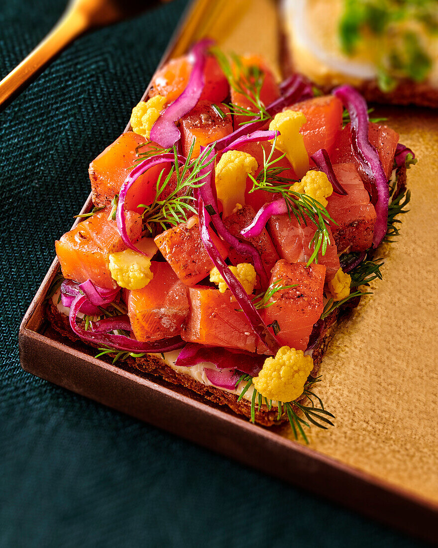 Bread topped with marinated salmon on a gold leaf serving platter