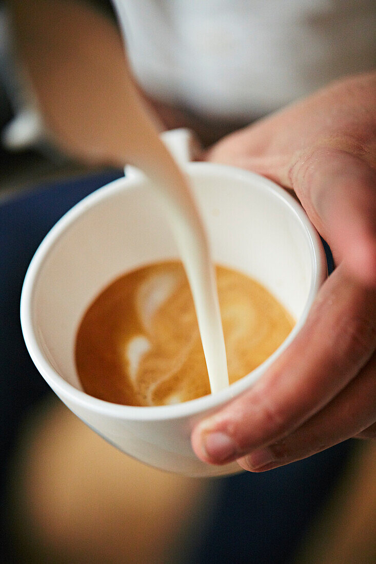 Barista pouring a flat wite with latte art