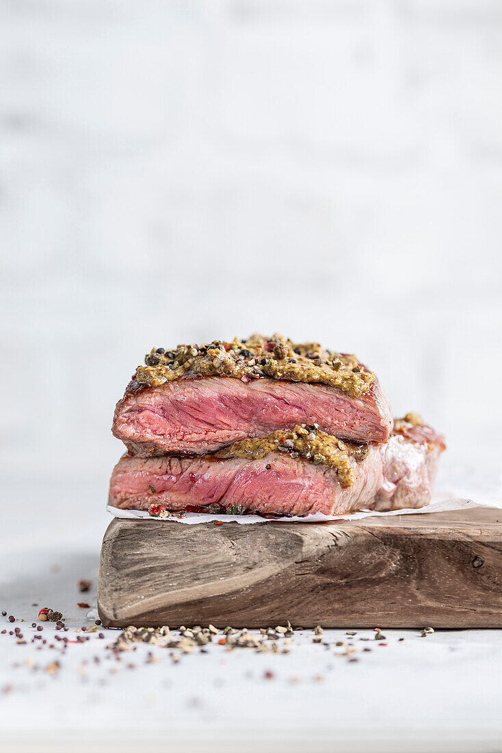Roast beef with a mustard crust on a wooden board (close-up)